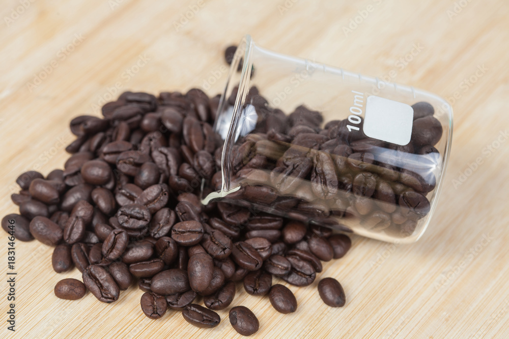 Fototapeta premium Dry coffee beans in test tube on wood background