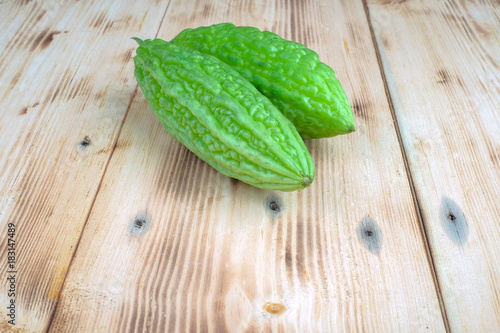 Fresh bitter melon or bitter gourd (Momordica charantia) over pine wood grain