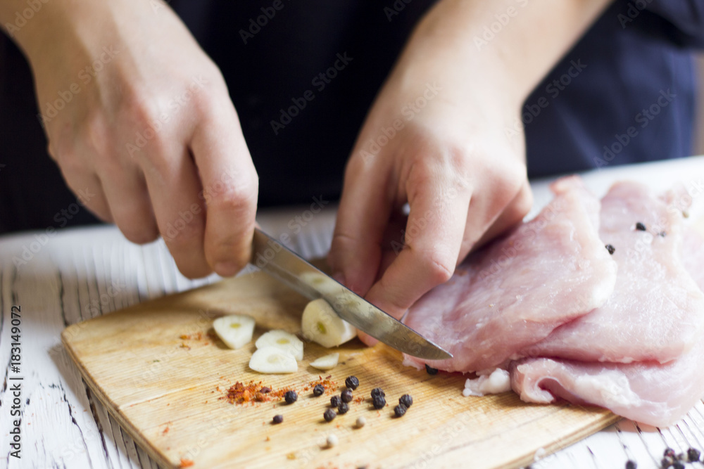 hands of chef cutting garlic on Board for seasoning meat