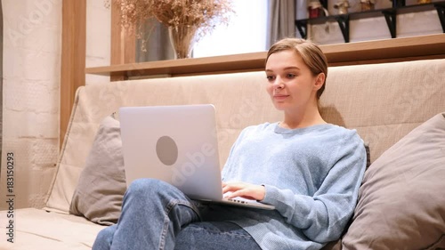 Excited Woman Celebrating Success while Working on Laptop, Sitting on Couch photo