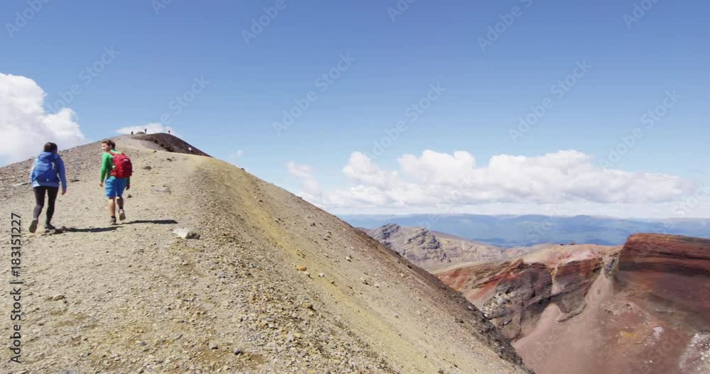 People hiking on nature trek in mountains on sunny day. Man and woman couple backpackers walking towards summit in Tongariro National Park, New Zealand. People living healthy lifestyle. SLOW MOTION. People hiking on nature trek in mountains on sunny day. Man and woman couple backpackers walking towards summit in Tongariro National Park, New Zealand. People living healthy lifestyle. SLOW MOTION.