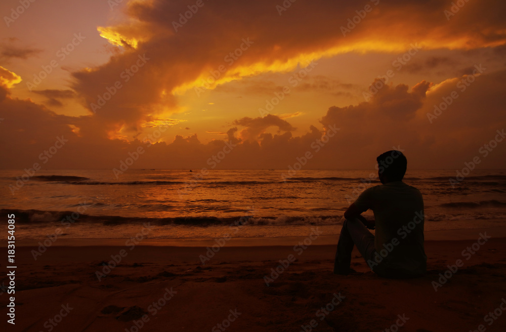 Thoughtful young man sitting and watching the sunset. 
