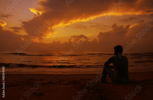 Thoughtful young man sitting and watching the sunset.  © V.R.Murralinath