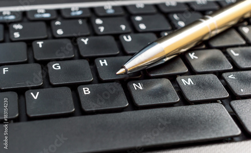 Pen on the laptop keyboard. Close up.