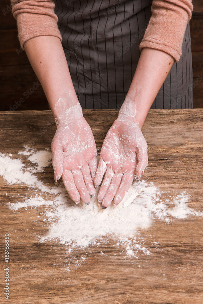 Baking craftsmanship. Woman hands making a dough from flour on wooden surface. Business bakery food industry concept