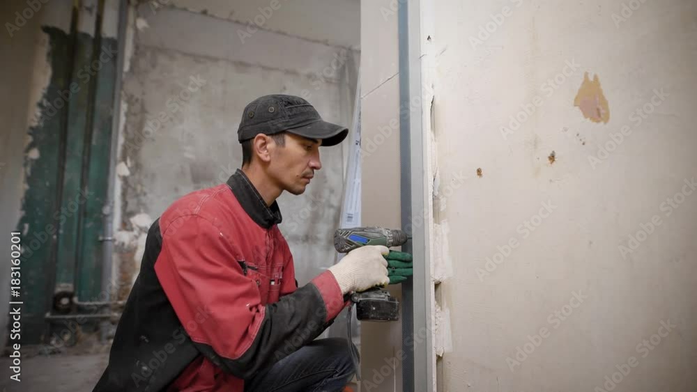 Man using tool fixing overlaps on wall in building Man using tool fixing overlaps on wall in building