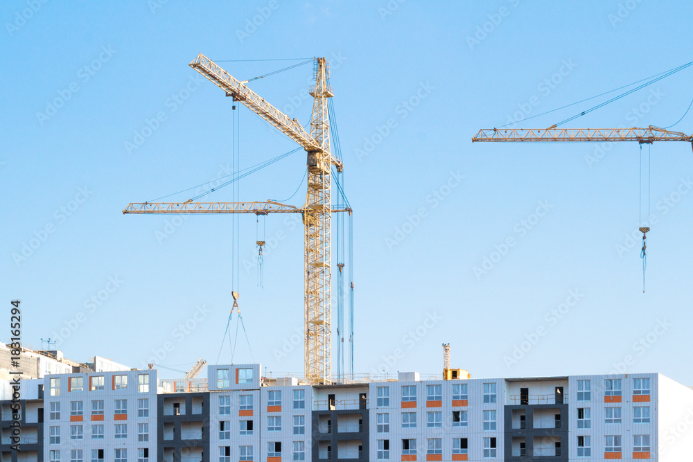 Cranes and building construction site against blue sky Cranes and building construction site against blue sky