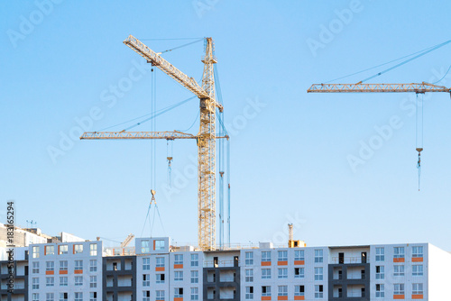 Cranes and building construction site against blue sky