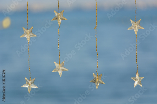 Decorative bohemian LED light wires with stars hanging on bright blue beach and blurred background