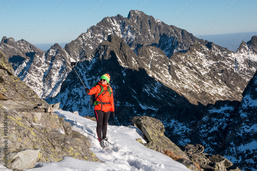 Successful woman backpacker taking selfie, enjoy the view on snow mountain peak.