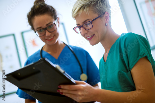 Close up view of two professional nurses with eyeglasses checking the patient papers in a doctors office. photo