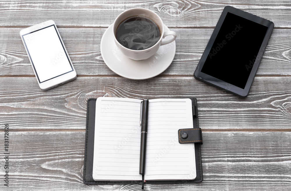 On a wooden table there is a cup of coffee, a cell phone, an address book, a pen, money On a wooden table there is a cup of coffee, a cell phone, an address book, a pen, money