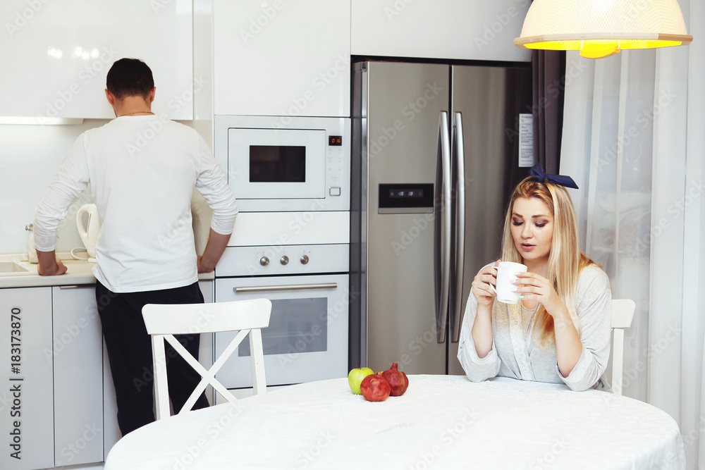 Beautiful couple drinking tea, sitting in the kitchen at home Beautiful couple drinking tea, sitting in the kitchen at home