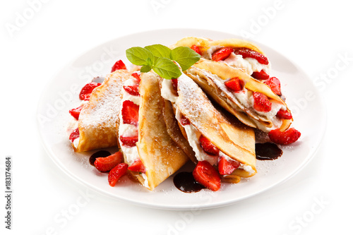 Crepes with strawberries and cream on white background 
