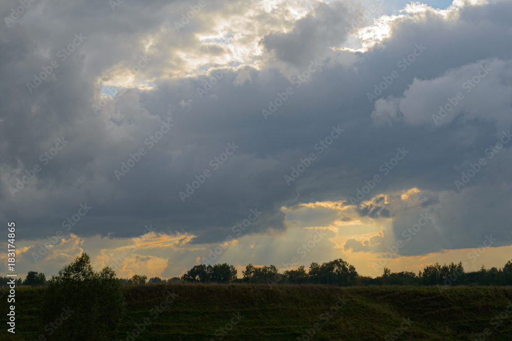 dark cloudy sky with clouds over a green field