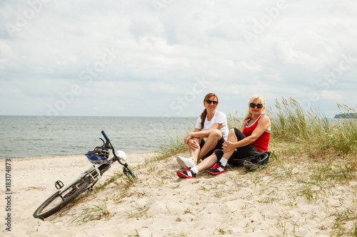 Women resting after riding bike on the beach 
