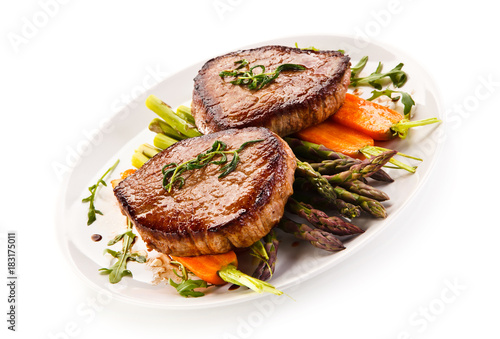 Grilled beef steaks with asparagus and carrots on white background 