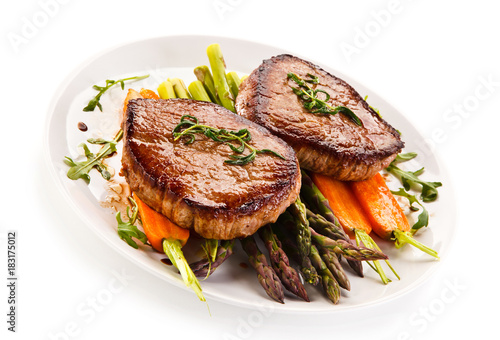 Grilled beef steaks with asparagus and carrots on white background 