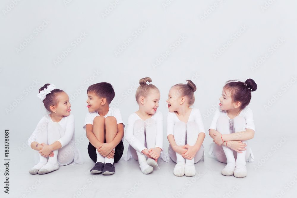 Naklejka premium Cute little kids dancers on white background. Choreographed dance by a group of small ballerinas practicing at a classical ballet school