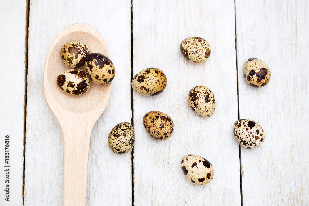 Group of quail eggs and a wooden spoon on a wooden background. Flat lay Group of quail eggs and a wooden spoon on a wooden background. Flat lay