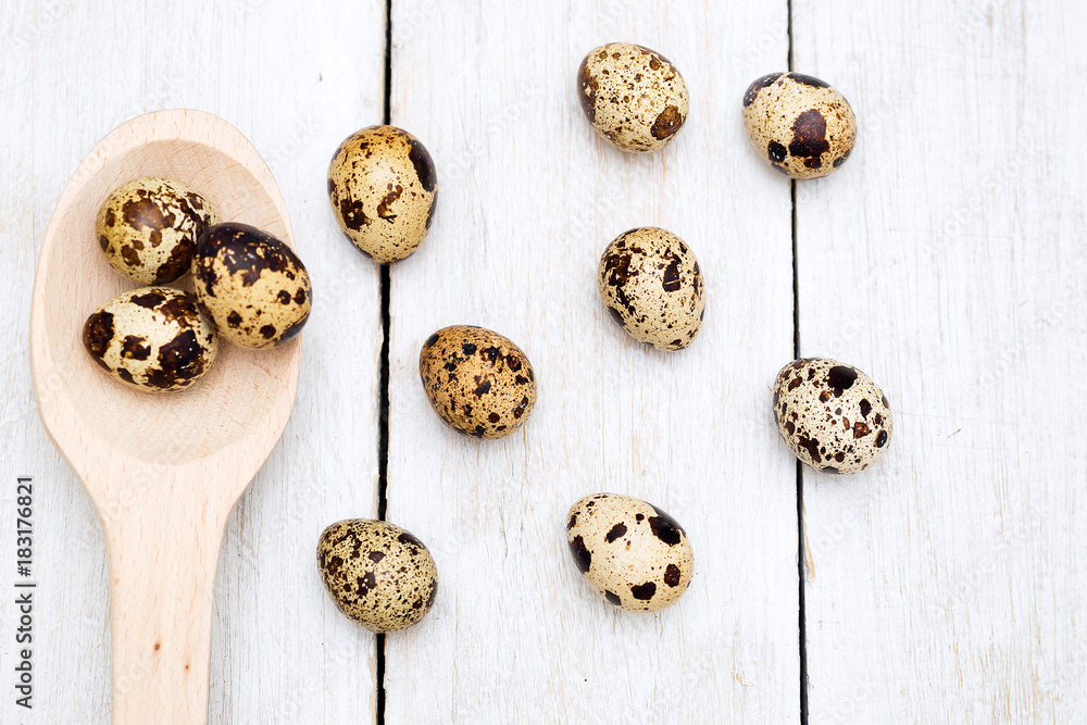 Quail eggs and a wooden spoon on a wooden background. Flat lay Quail eggs and a wooden spoon on a wooden background. Flat lay