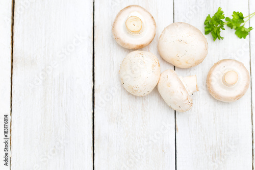 Fresh organic champignon mushrooms on white wood background. Copy space