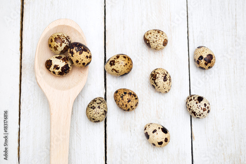 Group of quail eggs and a wooden spoon on a wooden background. Flat lay