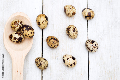 Quail eggs and a wooden spoon on a wooden background. Flat lay