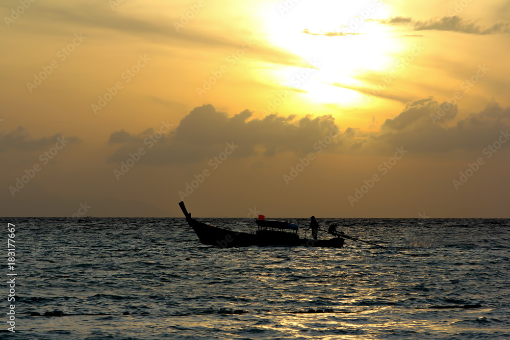Fisherman on the boat over dramatic sunse