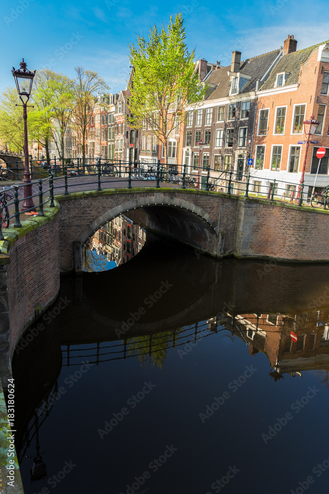 Stone bridge over canal with mirror reflections, Amsterdam, Netherlands