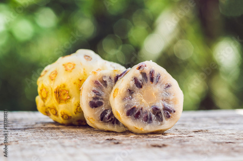 fresh noni fruit and noni slice on wooden background and space.slice of noni fruit with space on wooden background photo