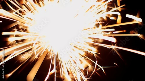 Bengal light burning with bright sparkles on black background. Close-up video.