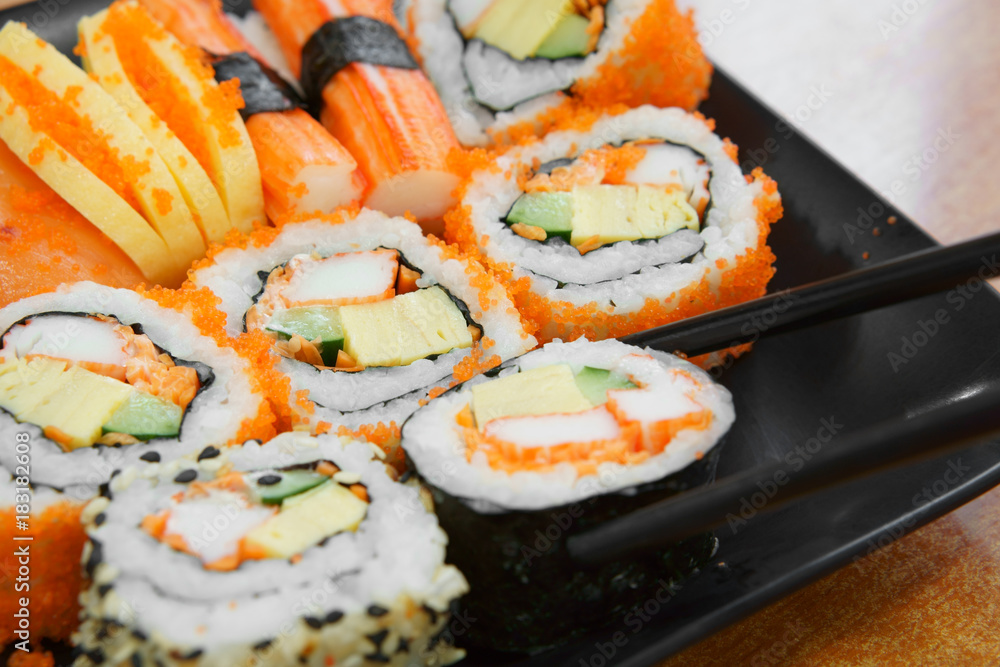 delicious sushi roll seaweed with salmon raw shrimp eggs and sesame on black dish and wood table with chopsticks for lunch or dinner at japanese food restaurant with space delicious sushi roll seaweed with salmon raw shrimp eggs and sesame on black dish and wood table with chopsticks for lunch or dinner at japanese food restaurant with space