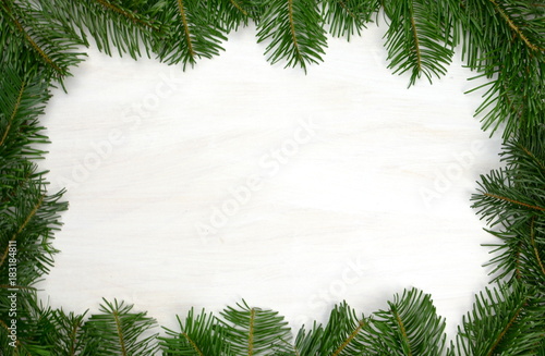 einfacher Rahmen aus Tannenzweigen und weißem, hellem Hintergrund aus Holz