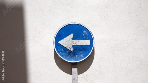 Blue direction arrow sign next to wall