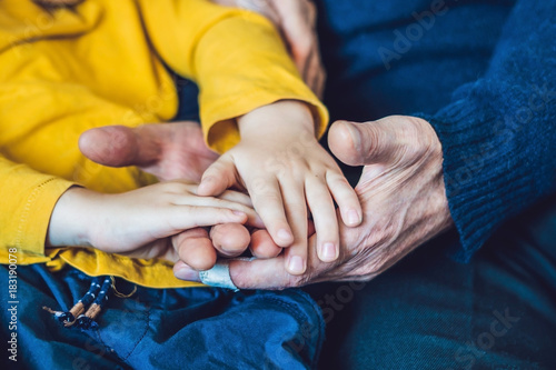 The hands of an elderly person and the hands of a child, the continuity of generations, the care of the elderly photo