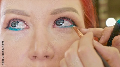 Make-up artist applying makeup to model's eye. Close up view.