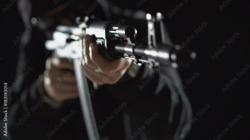 Armed man in black simulates shooting a machine gun. Bandit with weapons in hand on a black background. The criminal scene. Hands with a gun close-up Armed man in black simulates shooting a machine gun. Bandit with weapons in hand on a black background. The criminal scene. Hands with a gun close-up