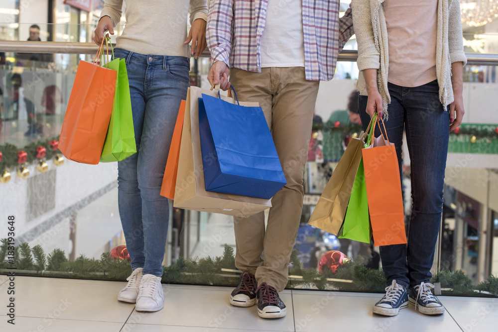 Group of young people with shopping bags doing shopping together in