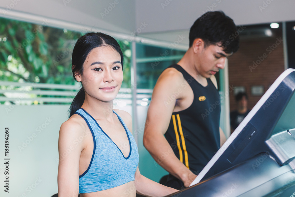 Young woman stand on treadmill with towel in the gym