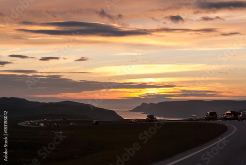 A column of cars on a winding road at sunset, Mageroya island, Norway