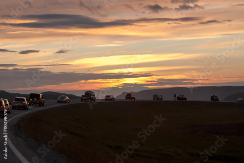 A column of cars on a winding road at sunset  Mageroya island  Norway