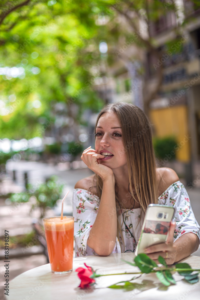 Romantic cute girl is sitting in the cafe and video chatting with red rose on the table. Dating and love concepts. Human emotions. Romantic cute girl is sitting in the cafe and video chatting with red rose on the table. Dating and love concepts. Human emotions.