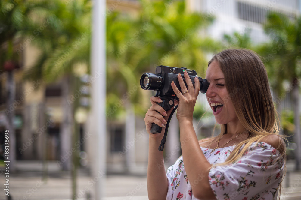 Tenerife. Spain. Cute blonde girl is observing and filming streets in Santa Cruz de Tenerife. Girl travels concept. Travel to Canary Islands. Tenerife. Spain. Cute blonde girl is observing and filming streets in Santa Cruz de Tenerife. Girl travels concept. Travel to Canary Islands.