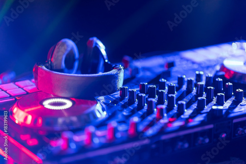 The DJ console cd mp4 deejay mixing desk Ibiza house music party in nightclub with colored disco lights.
