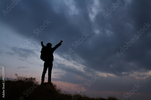 silhouette of winning success man on the top of a mountain
