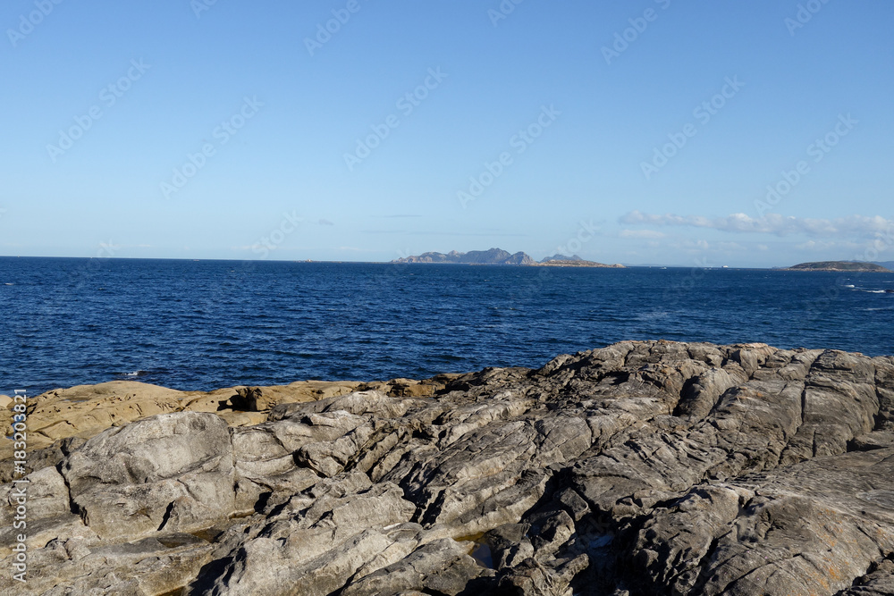 Rocky coast by the ocean during sunny day, clear blue sky Rocky coast by the ocean during sunny day, clear blue sky