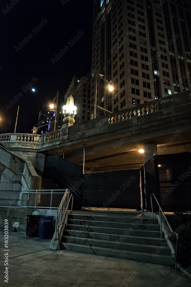 City stairs from riverwalk to bridge at night with moon in Chicago. City stairs from riverwalk to bridge at night with moon in Chicago.