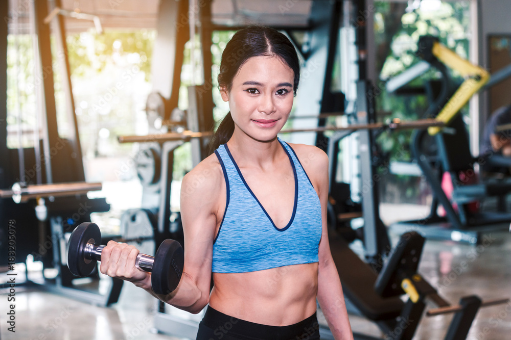 Sporty woman holding dumbbells with towel in the gym Sporty woman holding dumbbells with towel in the gym