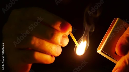 Man lights up a machstick with the matchbox in the darkness. Slow motion. Oxygen and sulfur mixture burns steadily, igniting the matchstick to produce a usable flame. Recorded at 96 fps, Running at 25